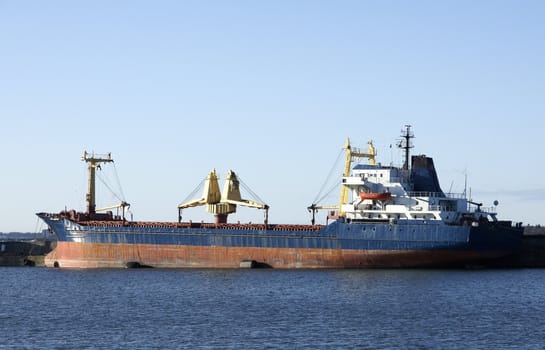 The cargoship costs in port on a background of the blue sky