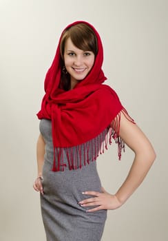 Young smiling woman in a red scarf. On grey background.