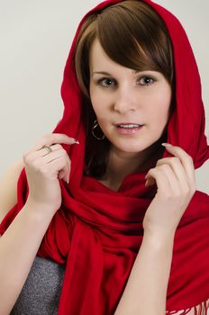 Young woman in a red scarf. On grey background.