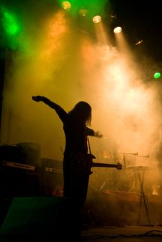 Unrecognizable musician on the stage, laser show and smoke 