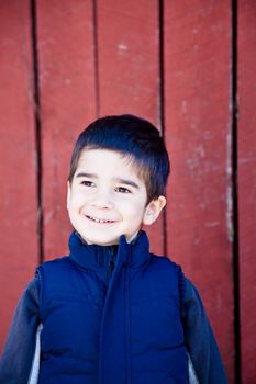 Little boy looking up and to the left in front of red textured background with a happy joyful expression.