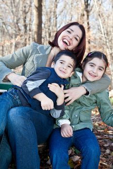 Family portrait of a happy laughing mother hugging smiling boy and girl.