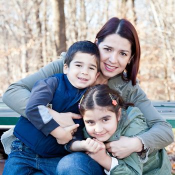 Family portrait of a smiling mother hugging a boy and girl.