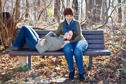 Mother holding her daughter on a park bench.