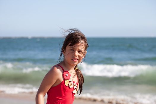 Little girl with a puzzled and surprised expression on the beach by the ocean.