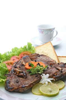closeup of T Bone Pepper Steak dressing by vegetable and bread  with Coffee cup