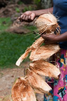 Coconut in female hands with removed shell as a part of  traditional twines and corns production in Asia