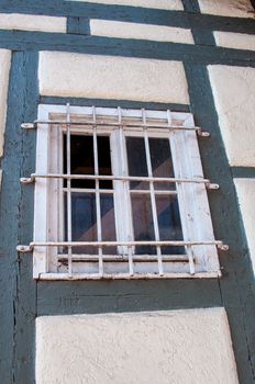 Old wooden framework facade of a half timbered house with barred window