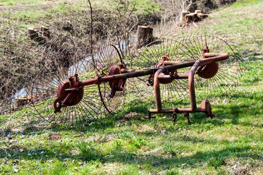 blades of an old hay rake left on a meadow field