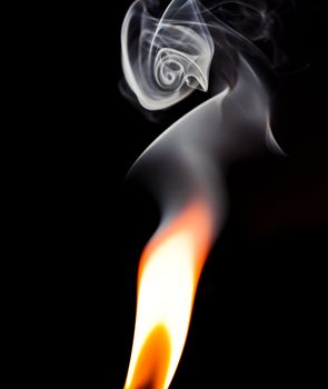 Flame isolated against a black background with smoke swirling above