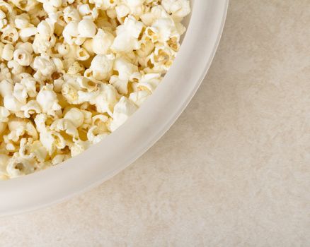 Bowl of buttered popcorn covering large portion of frame with copyspace in lower left