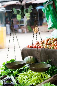 Old scales on open market with vegetables on shelves. Selective focus on the scales.