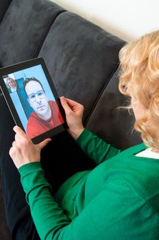 Middle-aged woman using video telephony on digital tablet pc