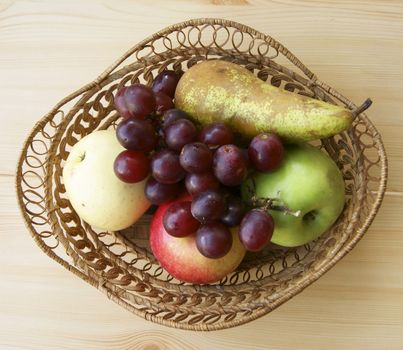 Ripe fruits in braided basket on table