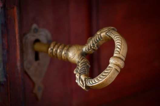 Antique beautiful bronze key in a door. Selective focus on the front.
