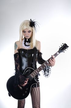 Alternative fashion girl playing guitar, studio shot over white background 