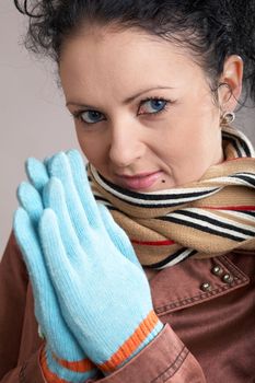 A girl in a striped scarf and blue gloves put her hands together