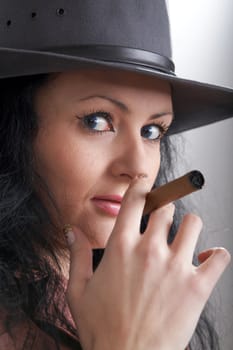 A woman in a grey hat smoking a cigar