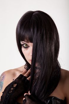Young gothic woman with yellow eyes and black long hair, studio shot 
