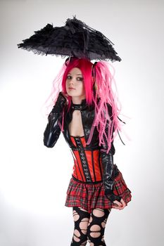 Funny gothic girl with umbrella, studio shot over white background 