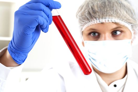 female chemist mixing liquids in test tubes, working in lab