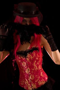 Artistic shot of cabaret girl wearing pink corset with feather boa, isolated on black background 