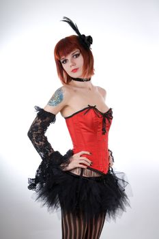 Cabaret girl in red corset and tutu skirt, studio shot over white background 