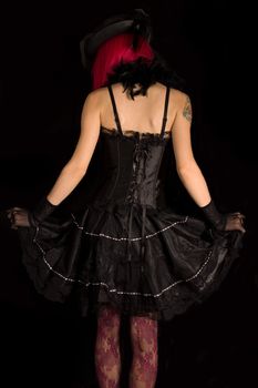 Rear view of cabaret girl in black corset dress, isolated on black background  