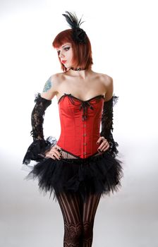 Attractive woman in red corset and black skirt, studio shot over white background 