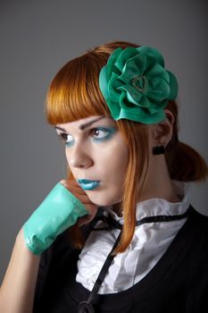 Portrait of young redhead woman with blue make-up, latex gloves and hair fascinator 