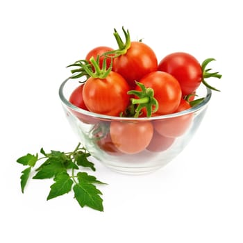 Small red tomatoes in a glass container with a green leaf isolated on white background