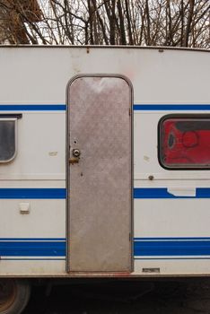 Old grungy aged caravan with metal door