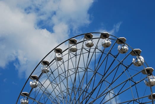 Ferris wheel on half, blue sky and white clouds