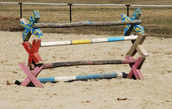 Painted wooden horse training hurdles on sand field