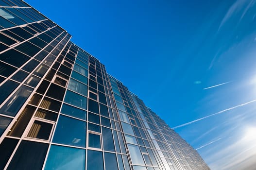 Glass wall of office building with deep blue sky on background