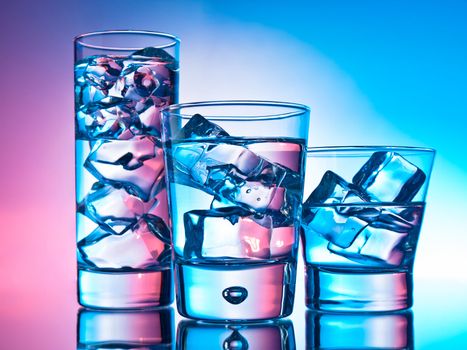 Three cocktails in different glasses on pink and blue background