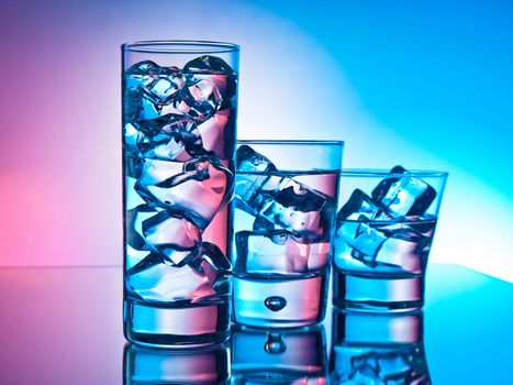 Three cocktails in different glasses on pink and blue background