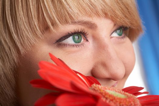 Girl's green eyes and a red flower close-up