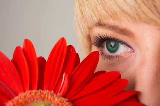 Girl's green eye and a red flower close-up