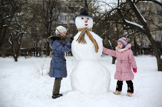Two little girls are doing great snowman