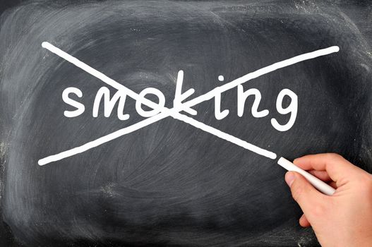 No smoking concept on a blackboard, crossing out with a hand holding chalk