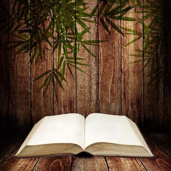 Open book on wooden table with bamboo leves pattern