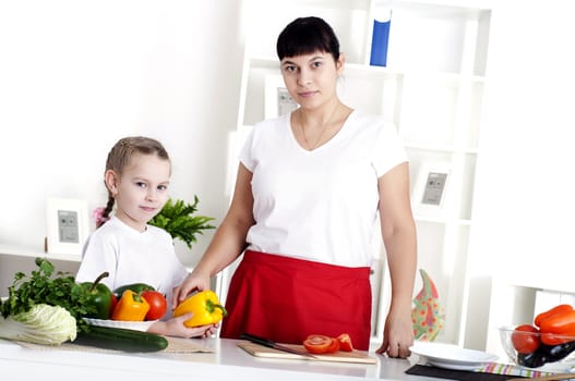 Mother and daughter cooking vegetable salad together