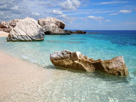 Big rocks and shallow emerald sea at Cala Mariolu, a beach in the Golfo di Orosei, Sardinia, Italy.