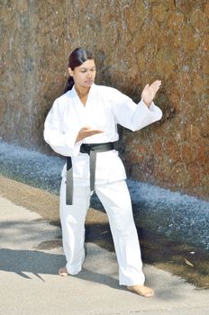 Female black belt champion karate player demonstrating various karate moves in the park