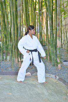 Female black belt champion karate player demonstrating various karate moves in the park