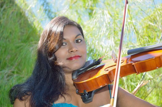 Attractive brunette musician providing live music in the park on her violin