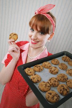 Retro housewife holding cookie tray full of chocolate cookie 