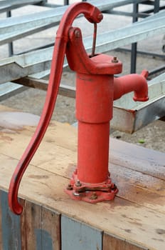 Traditional red Iron water pump on wood table