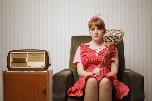Ironic portrait of a housewife retro sitting in an armchair